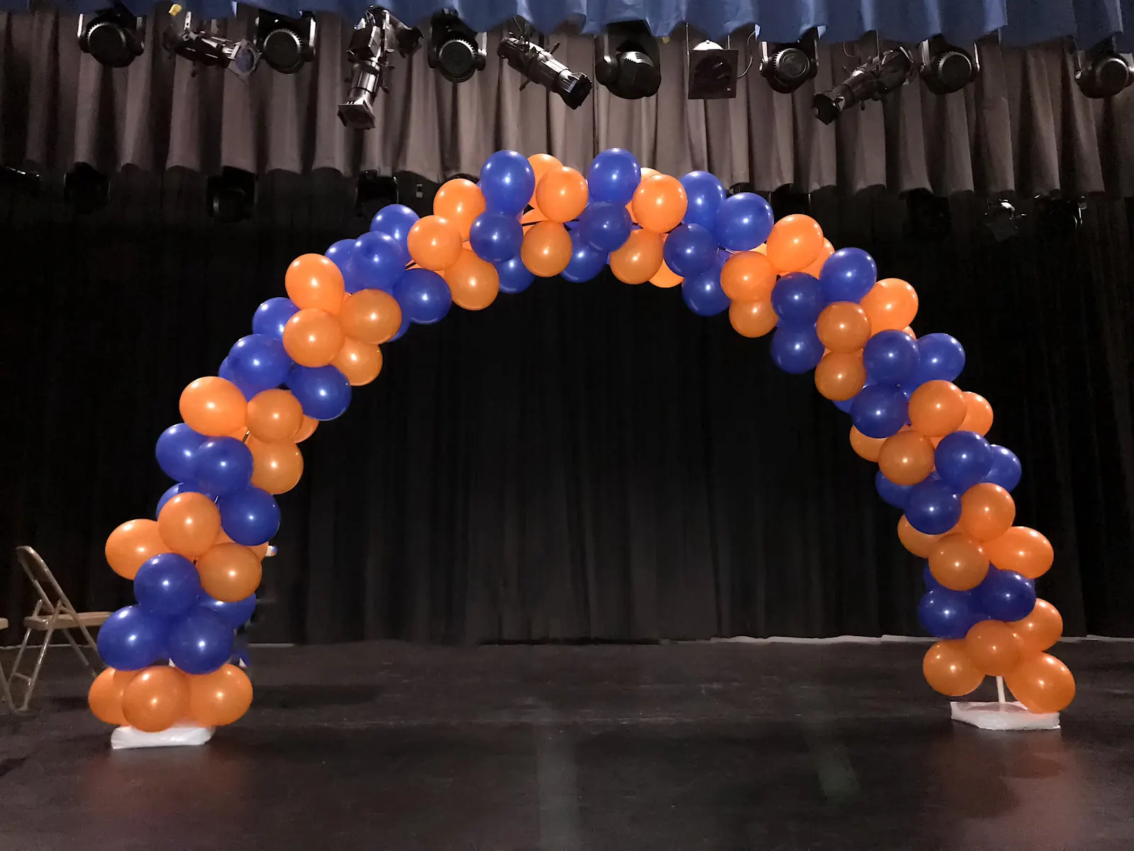 Orange and blue balloon arch on a school stage in Los Angeles