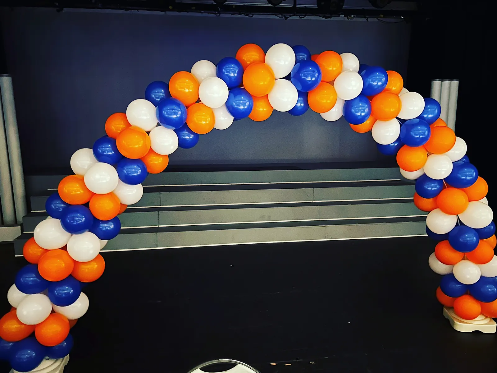 Orange, blue and white balloon arch in front of stage steps