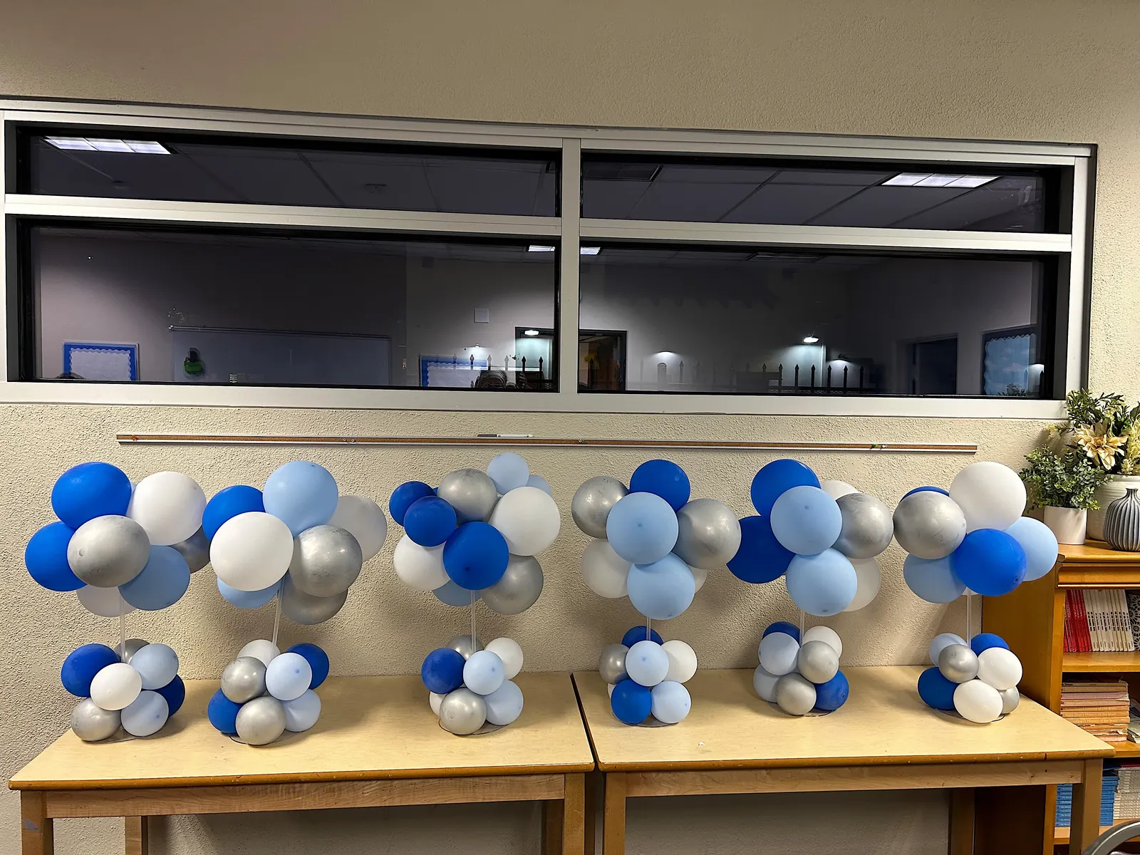 Row of blue, silver and white balloon centerpieces on classroom tables