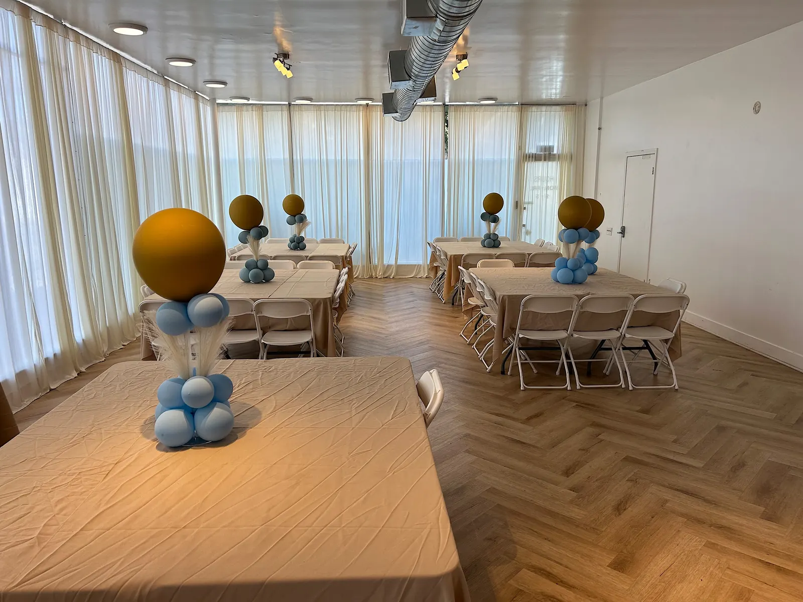 Gold and blue balloon centerpieces on tables in an event hall