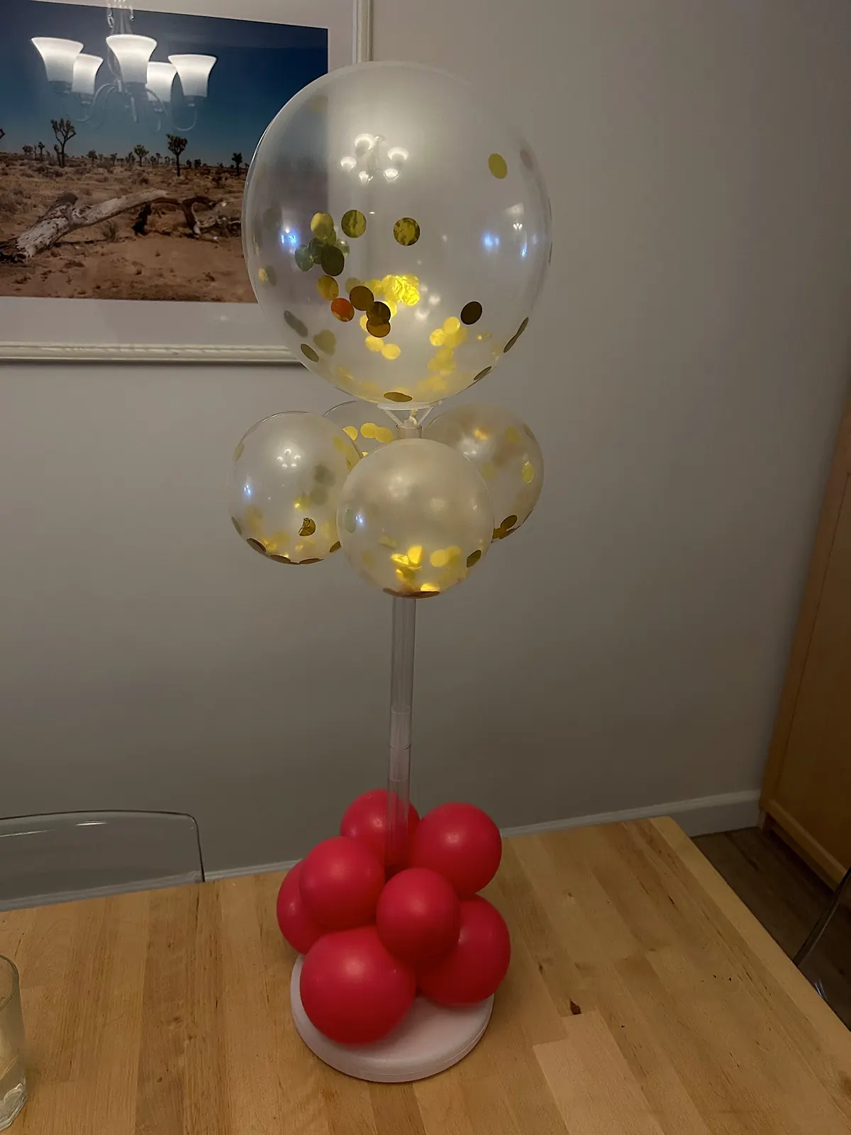 Centerpiece with a gold confetti balloon on a stem over a red balloon base