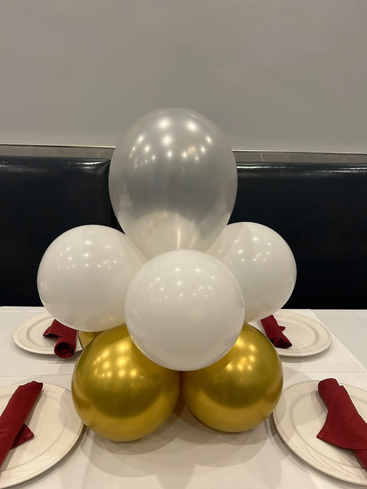 Gold, white and silver balloon centerpiece on a restaurant table setting