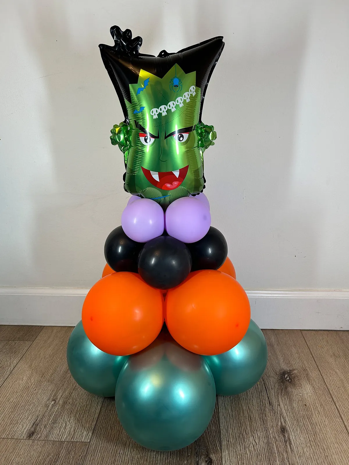 Halloween balloon centerpiece with a monster foil balloon over orange, black and teal
