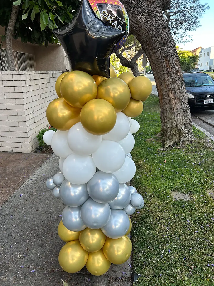 Gold, white and silver balloon column with a graduation star balloon outside a Los Angeles home