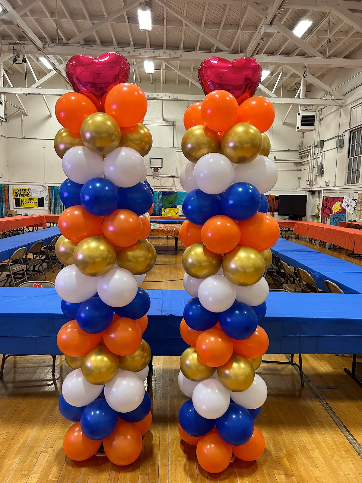 Pair of orange, blue, gold and white balloon columns with heart toppers