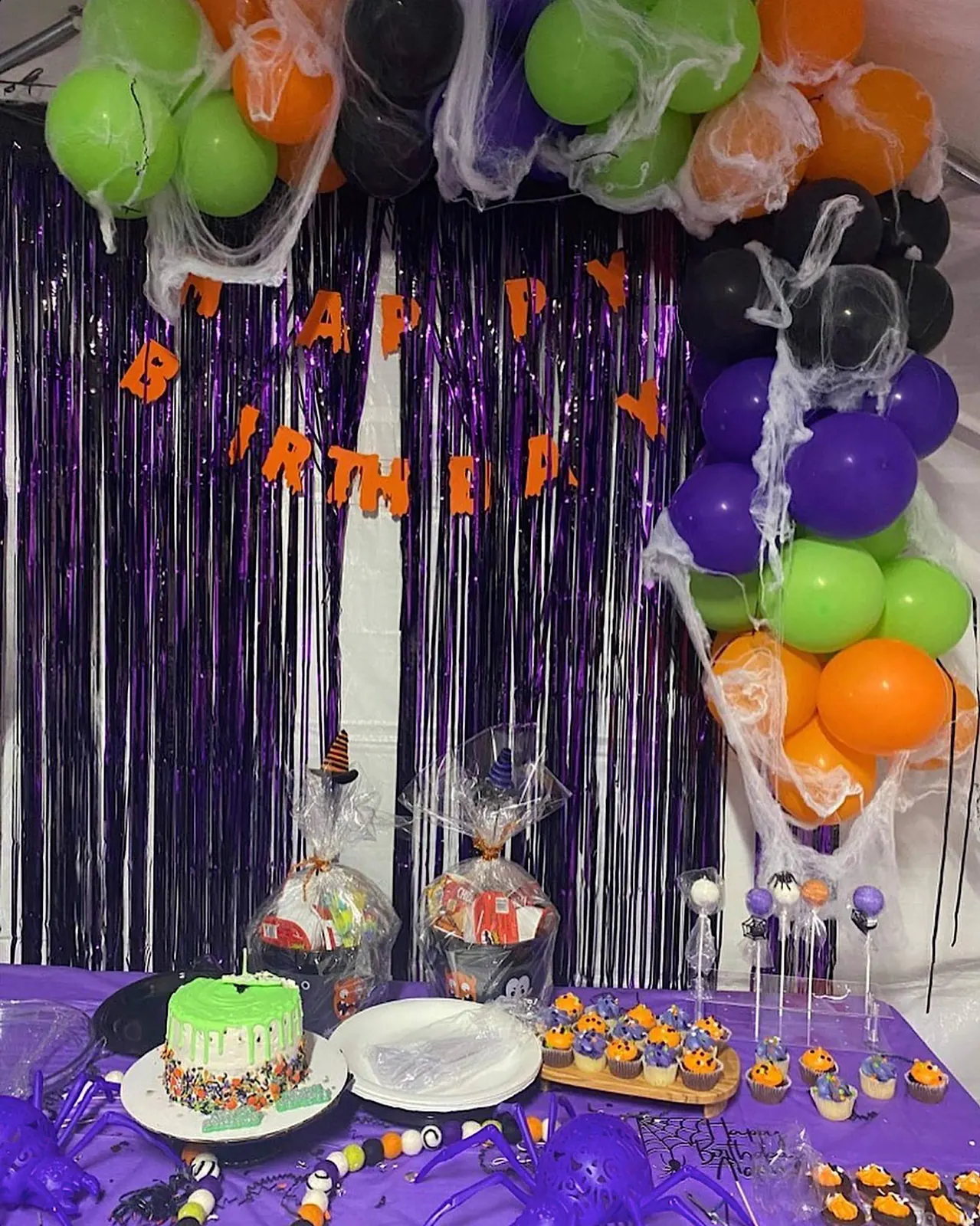 Purple, orange, green and black balloon garland at a Halloween birthday dessert table