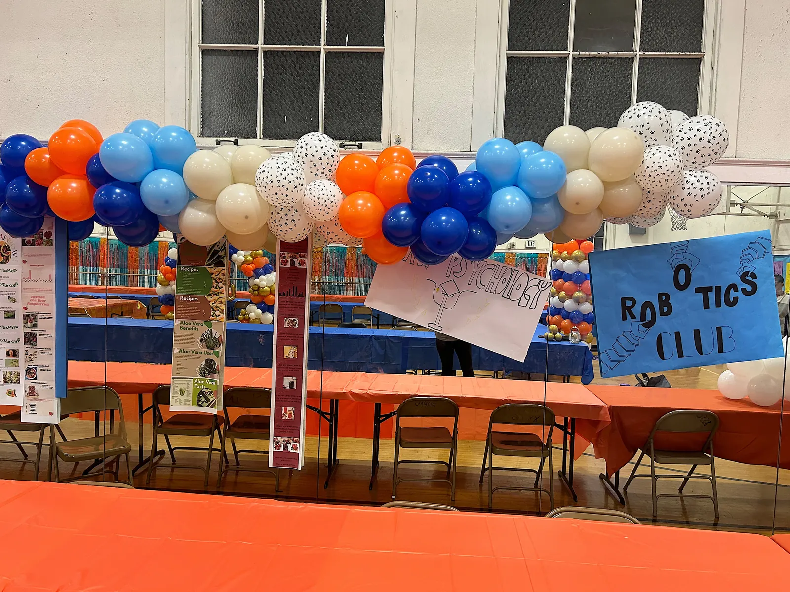 Orange, blue and cream balloon garland over a school robotics club display