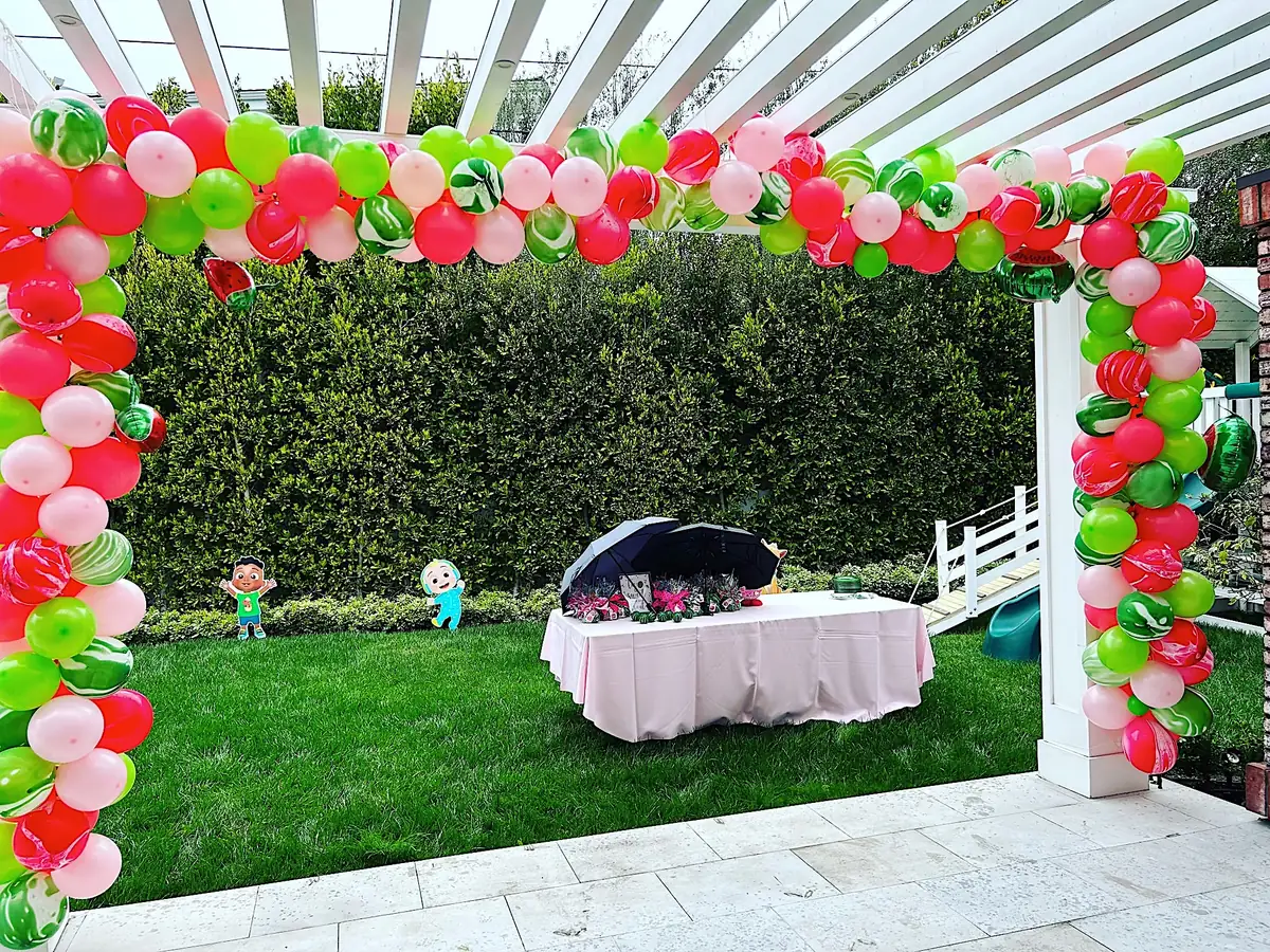 Pink and green balloon garland framing a backyard pergola in Los Angeles