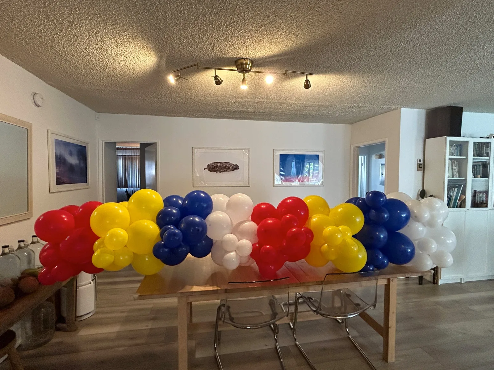 Red, yellow, royal blue and white balloon garland laid along a dining table at home