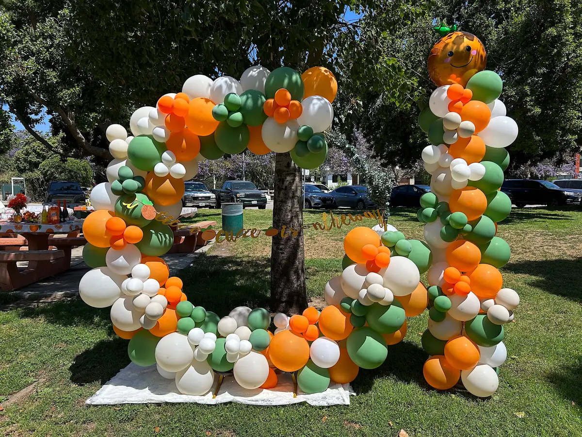 Orange, green and white circular balloon arch at a picnic in a Los Angeles park